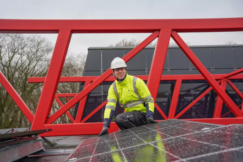 A man wearing its PPE working on solar panel
