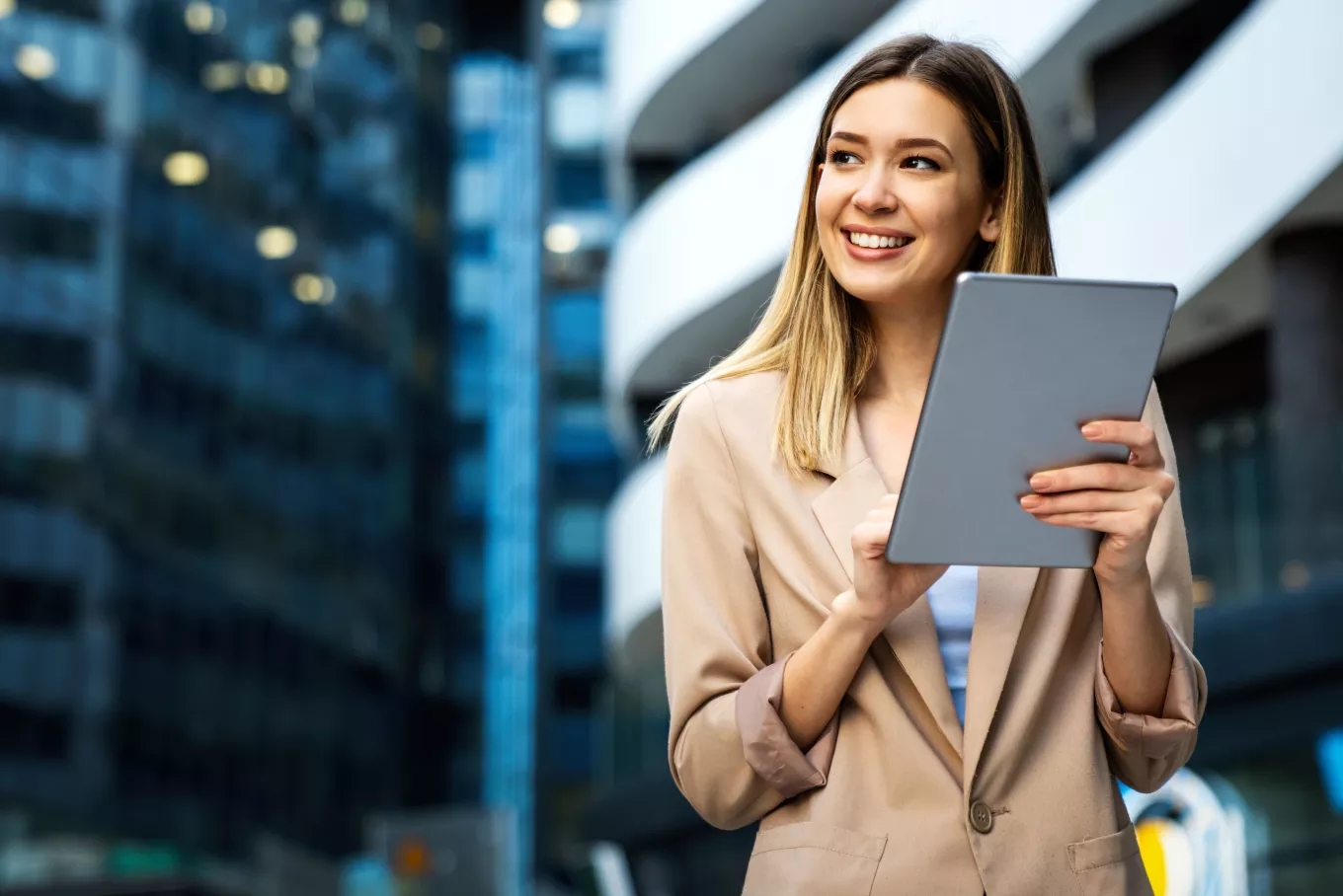 Portrait of a successful business woman using digital tablet in front of modern business building