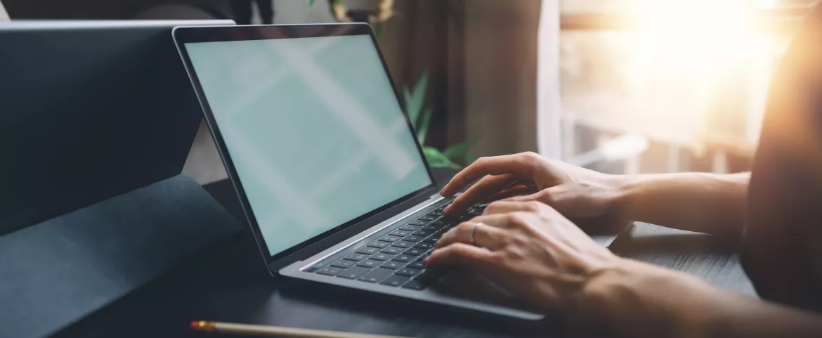 Female hands typing on laptop keyboard at the office.