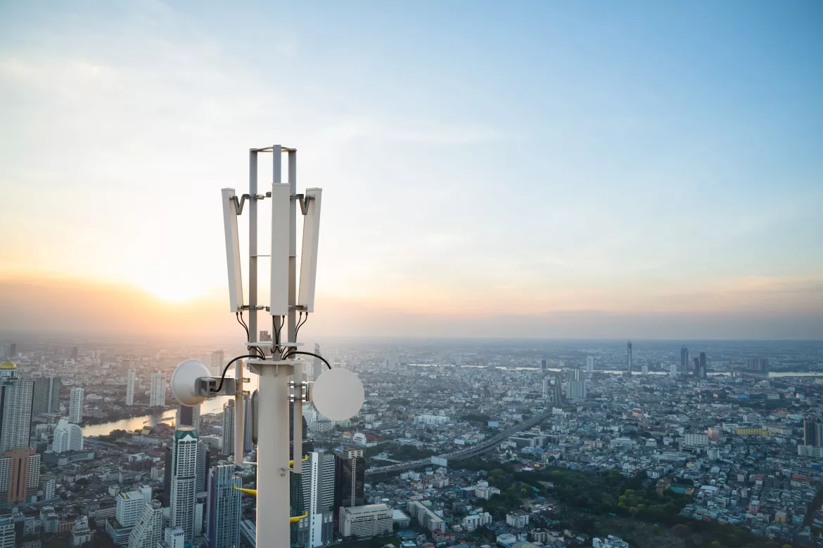 Telecommunication tower with 5G cellular network antenna on city background