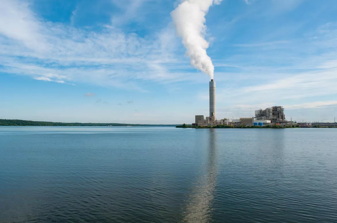 On a lake, a factory's chimney is emiting smoke in the background