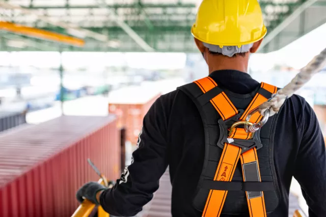 Construction worker use safety harness and safety line working on a new construction site project.