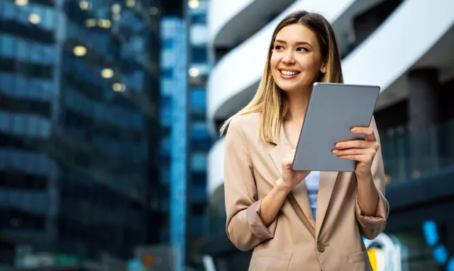 Portrait of a successful business woman using digital tablet in front of modern business building