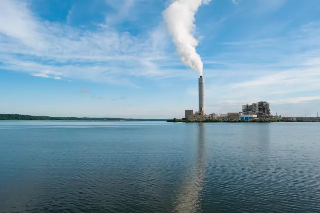 On a lake, a factory's chimney is emiting smoke in the background