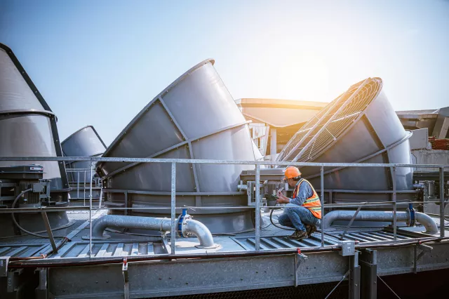 A engineer under checking the industry cooling tower air conditioner is water cooling tower air chiller HVAC of large industrial building to control air