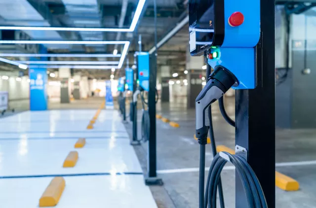 Electric car charging station for charge EV battery. Plug for vehicle with electric engine. EV charger. Clean energy. Charging point at car parking lot. Green power.