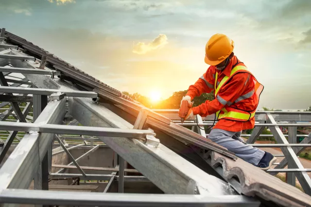 Builders in work clothes install new roofing tools, roofing tools, electric drill and use them on new wooden roofs with metal sheet