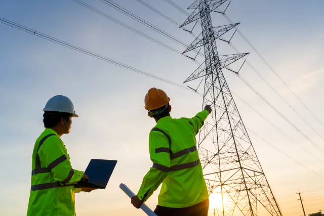 Manager Engineering and worker in standard safety uniform working inspect the electricity high voltage pole.
