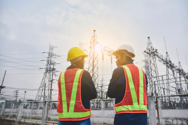 Man and Women Engineering standing communication at power plant electrical system background