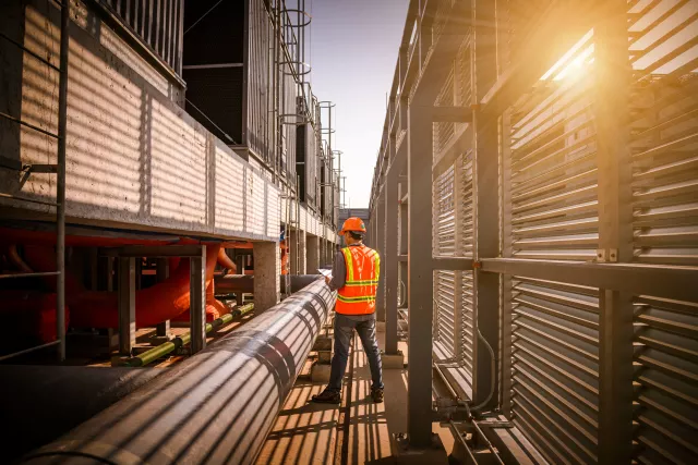 A engineer under checking the industry cooling tower air conditioner is water cooling tower air chiller HVAC of large industrial building to control air